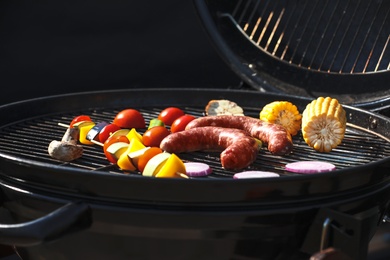 Tasty sausages and vegetables on modern barbecue grill