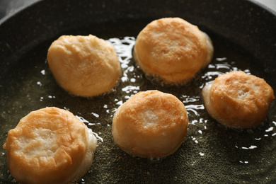 Photo of Cooking delicious donuts in hot oil, closeup