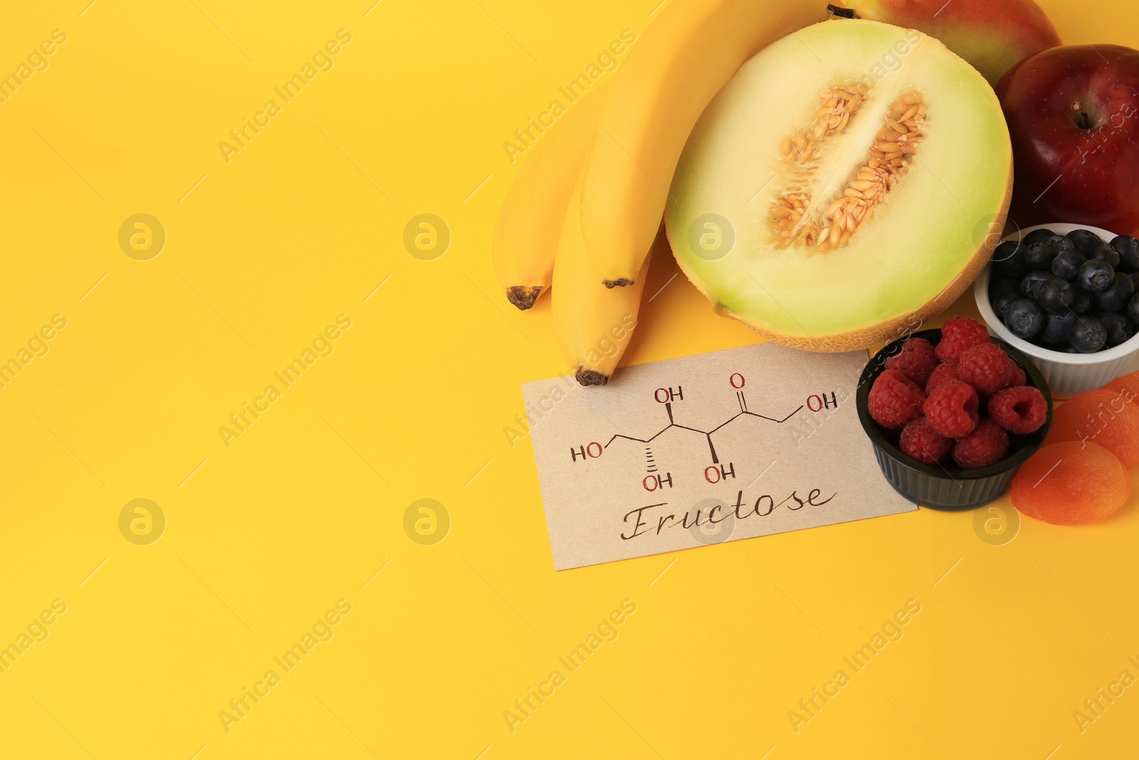 Photo of Card with fructose chemical structure, delicious fruits and berries on yellow background, above view. Space for text