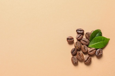 Fresh green coffee leaves and beans on light orange background, flat lay. Space for text