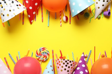 Photo of Flat lay composition with party decor and candies on yellow background, space for text