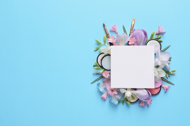 Makeup products, spring flowers and blank card on color background, flat lay. Space for text