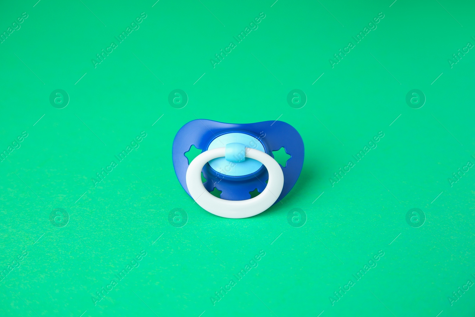 Photo of One blue baby pacifier on green background