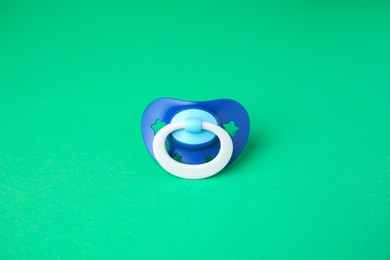 Photo of One blue baby pacifier on green background