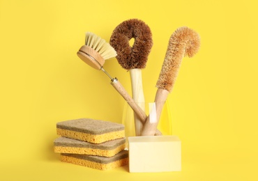 Photo of Cleaning supplies for dish washing on yellow background