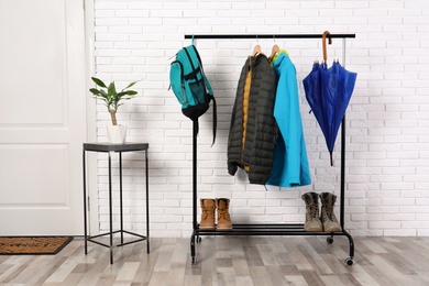 Stylish hallway interior with shoes and clothes on hanger stand