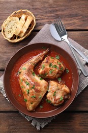 Photo of Tasty cooked rabbit meat with sauce served on wooden table, top view