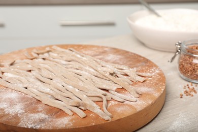 Photo of Uncooked homemade soba (buckwheat noodles) on wooden table, closeup