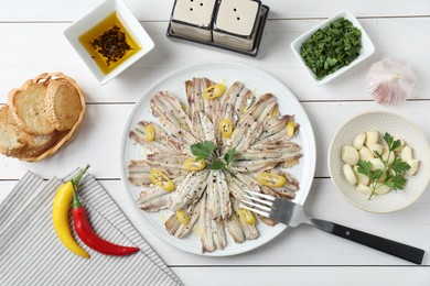 Tasty pickled anchovies served on white wooden table, flat lay