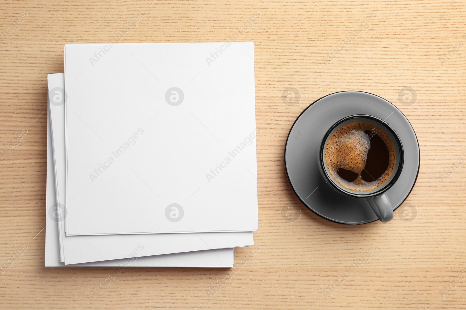 Photo of Blank paper sheets for brochure and cup of coffee on wooden background, flat lay. Mock up