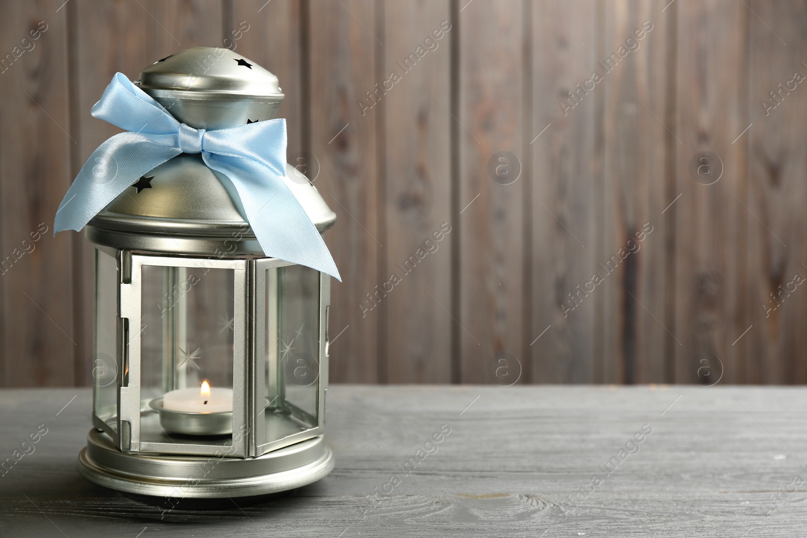 Photo of Beautiful decorative Christmas lantern with burning candle on grey wooden table. Space for text