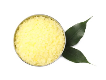 Photo of Yellow sea salt in bowl and green leaves isolated on white, top view
