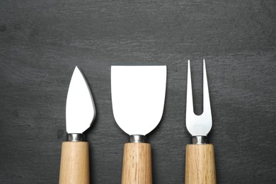 Photo of Cheese knives and fork on black background, flat lay