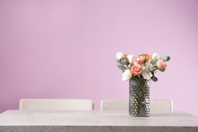 Vase with beautiful flowers as element of interior design on table in room. Space for text