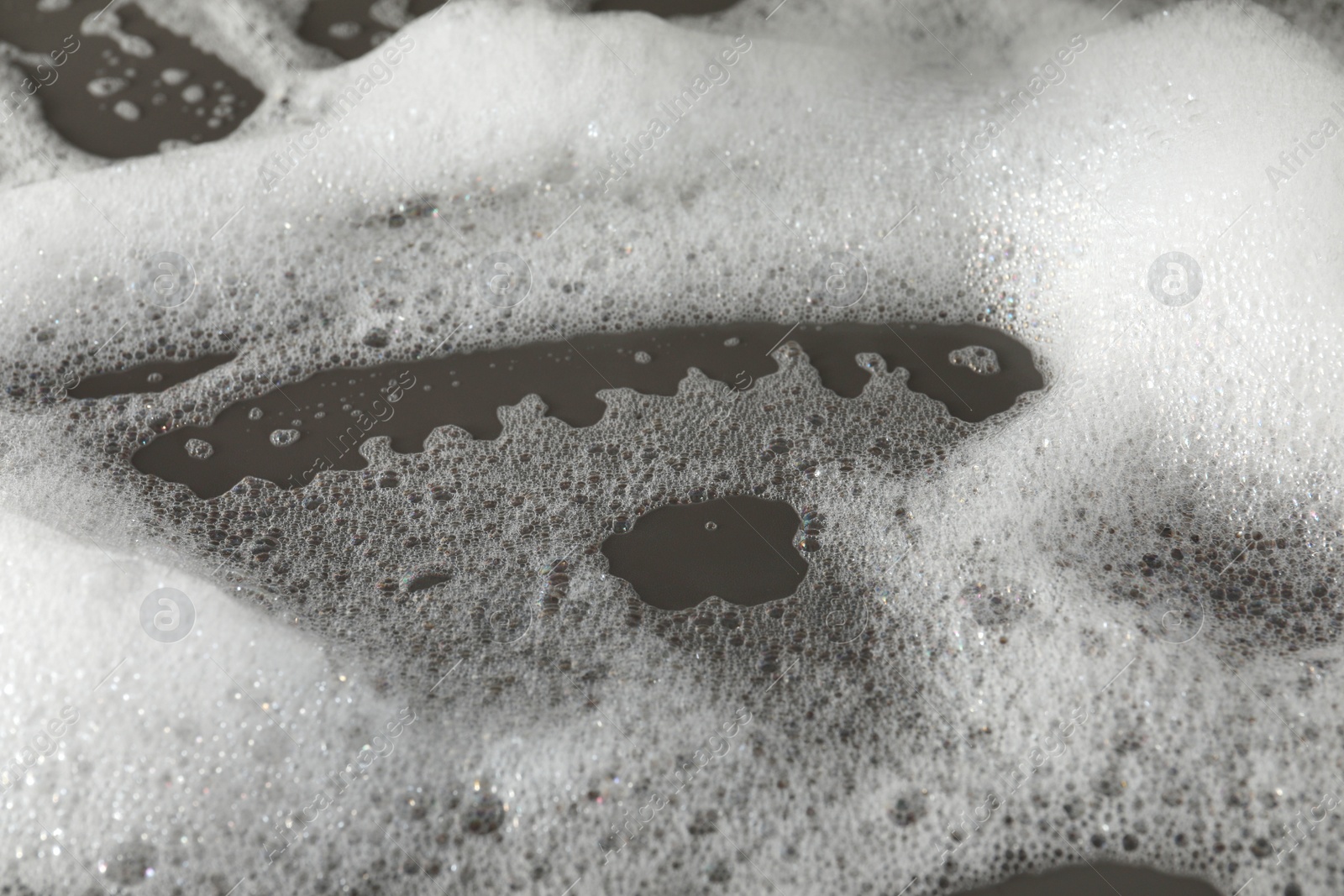 Photo of Fluffy bath foam on grey background, closeup