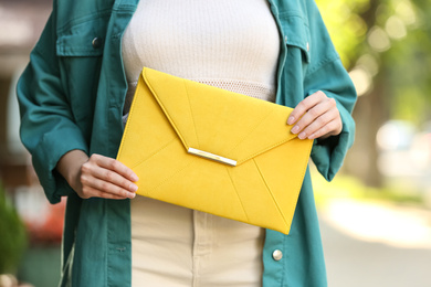 Photo of Young woman with elegant envelope bag outdoors on summer day, closeup