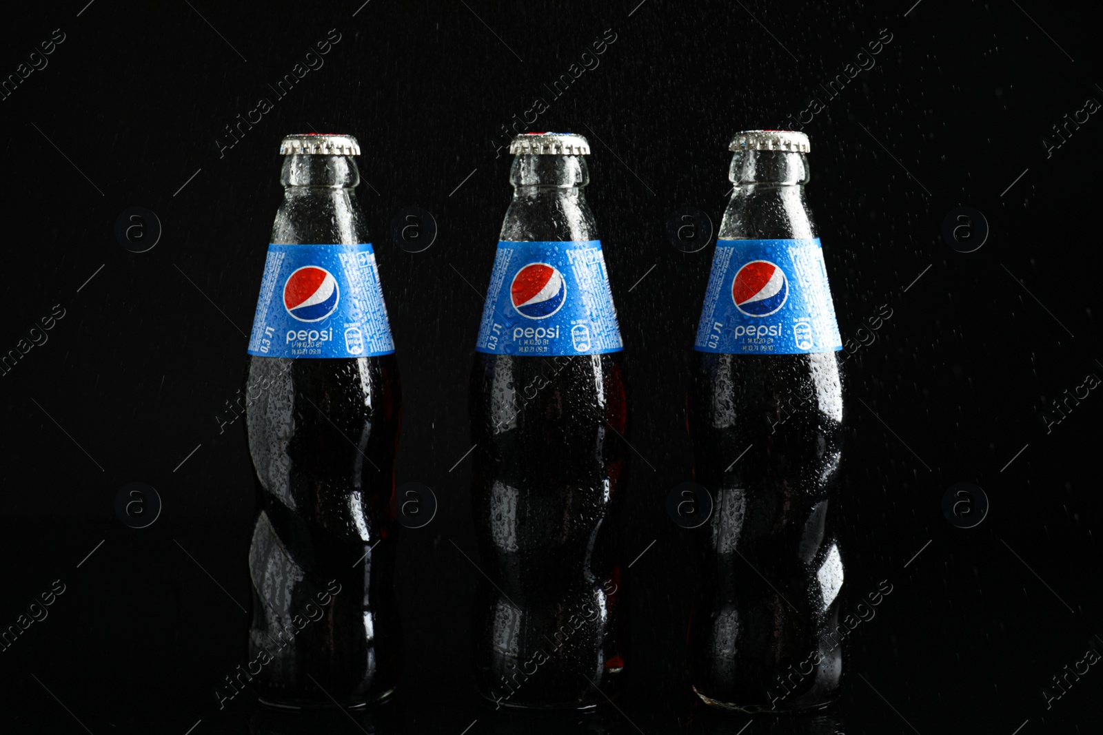 Photo of MYKOLAIV, UKRAINE - FEBRUARY 08, 2021: Glass bottles of Pepsi with water drops on black background