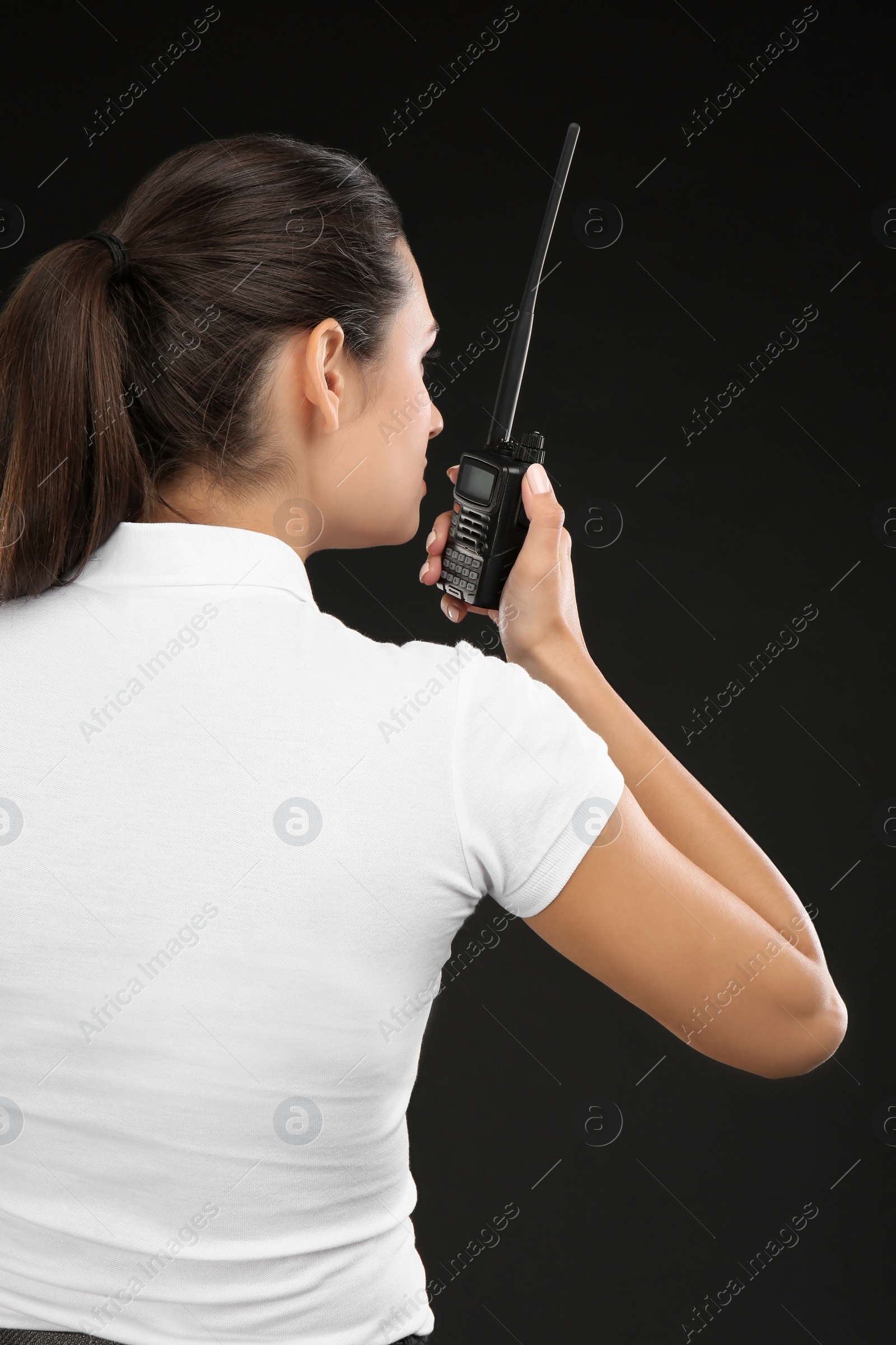 Photo of Female security guard using portable radio transmitter on dark background