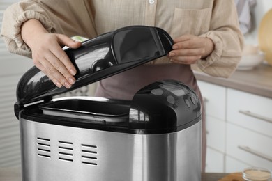 Woman using breadmaker machine in kitchen, closeup