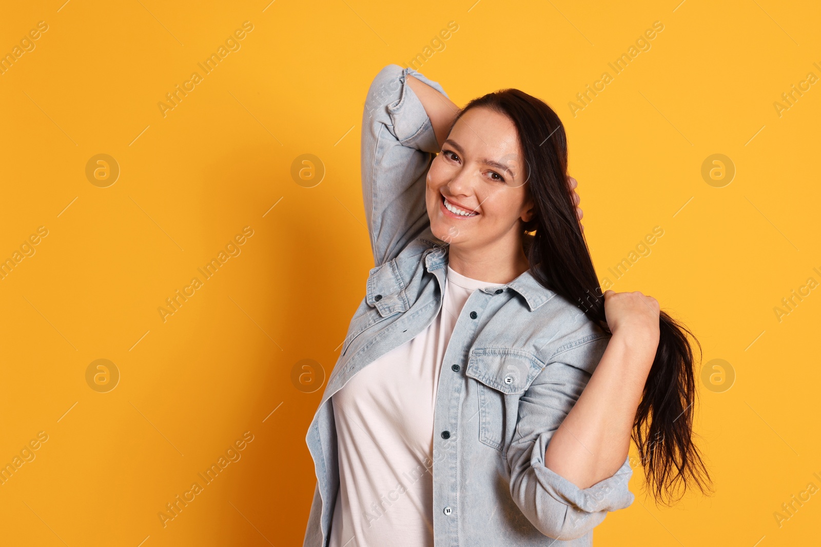 Photo of Beautiful overweight woman with charming smile on yellow background. Space for text