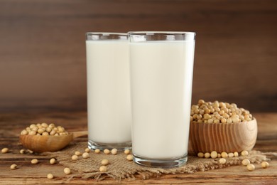 Glasses with fresh soy milk and grains on wooden table