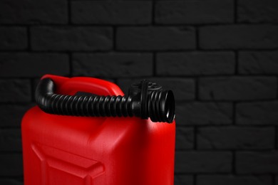 Photo of Red plastic canister against dark brick wall, space for text