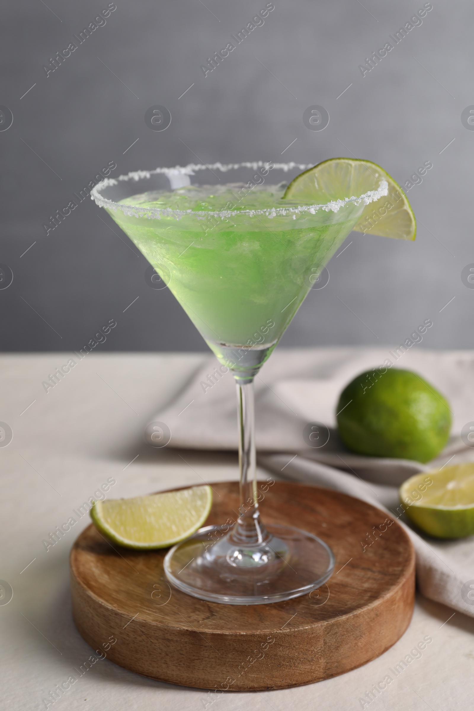 Photo of Delicious Margarita cocktail in glass and limes on light table