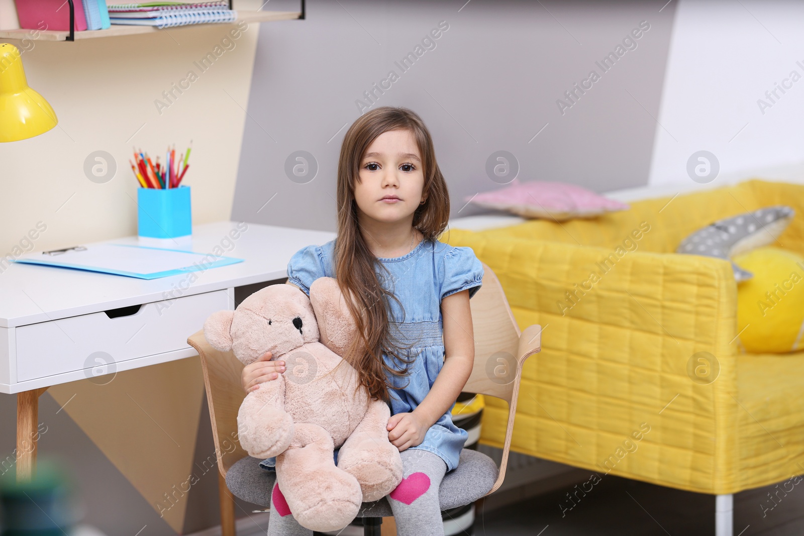 Photo of Cute little girl playing with toy bear at home