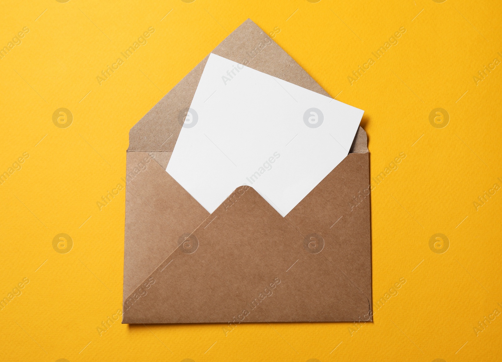 Photo of Blank sheet of paper in open letter envelope on orange background, top view