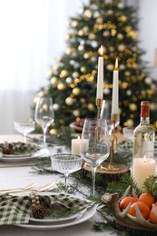 Christmas table setting with festive decor and dishware in room