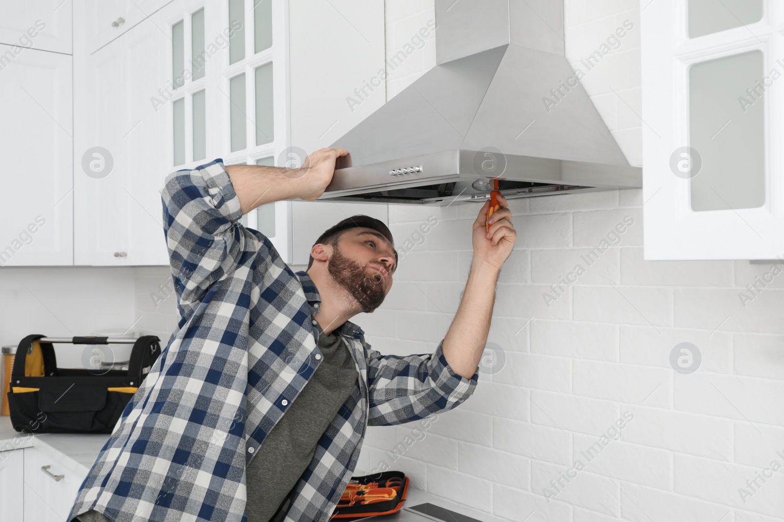 Photo of Man repairing modern cooker hood in kitchen