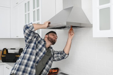 Man repairing modern cooker hood in kitchen