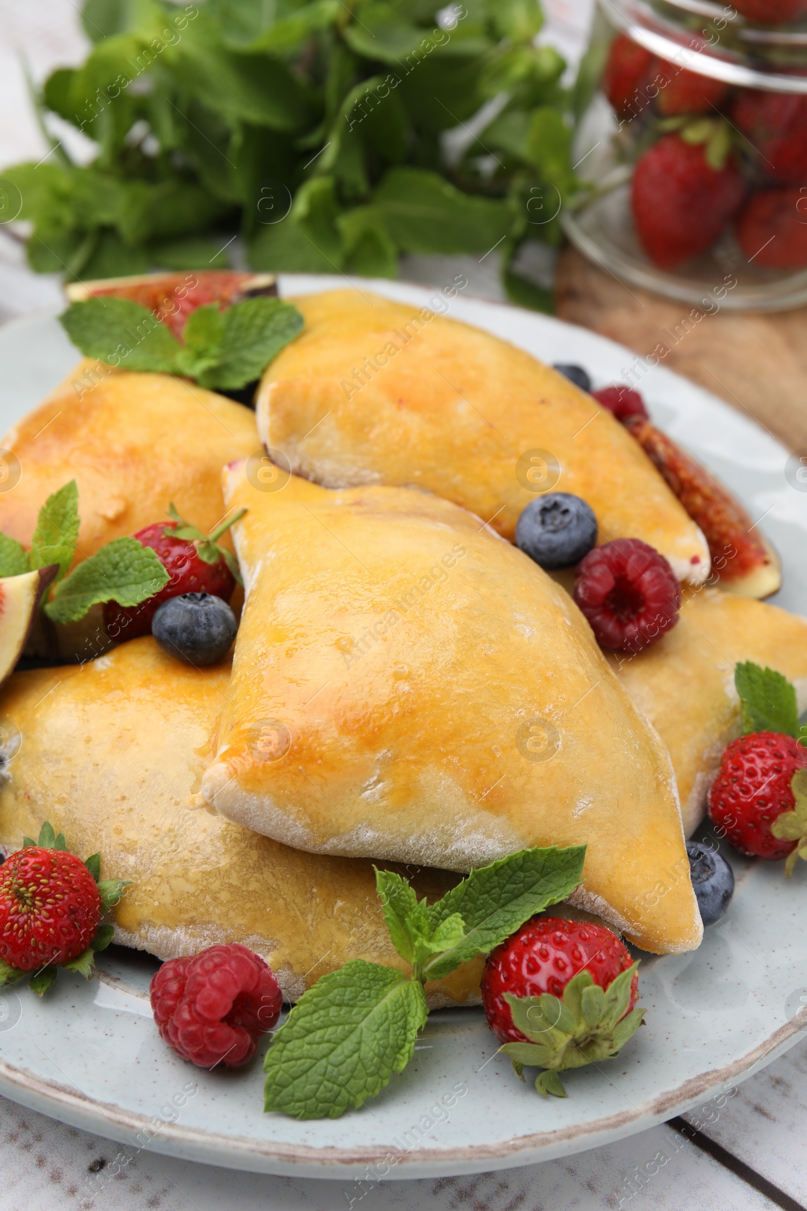 Photo of Delicious samosas with berries on white wooden table, closeup