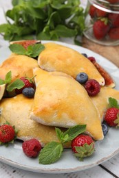 Delicious samosas with berries on white wooden table, closeup