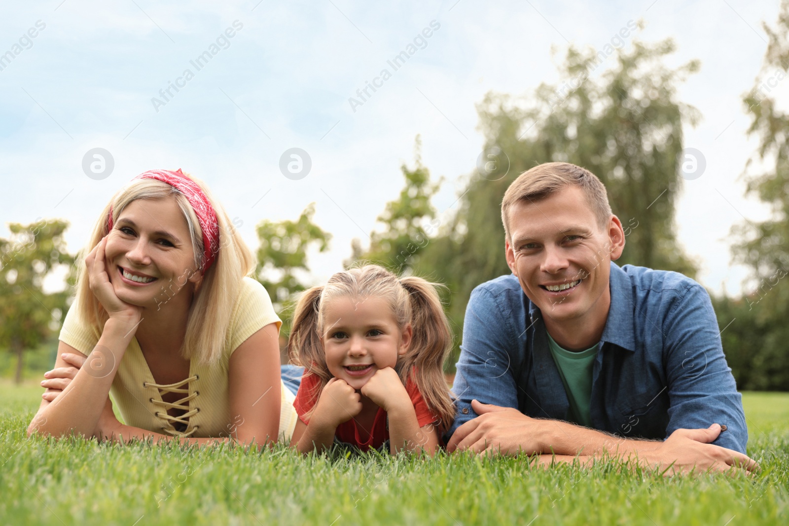 Photo of Happy family lying on green grass in park