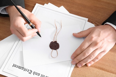 Photo of Male notary working with documents at wooden table, closeup