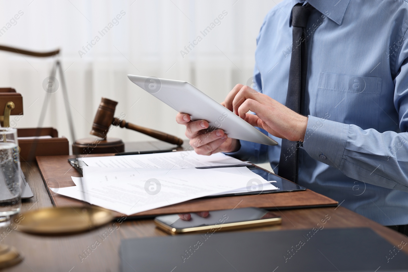 Photo of Lawyer using tablet at wooden table, closeup
