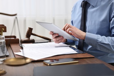 Photo of Lawyer using tablet at wooden table, closeup