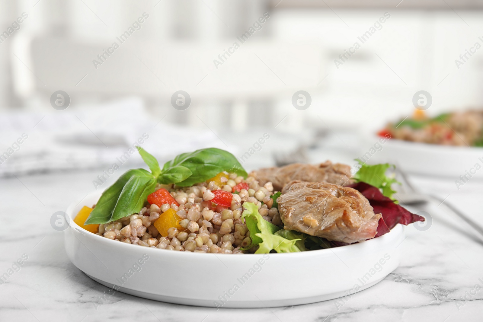 Photo of Tasty buckwheat porridge with meat on white marble table