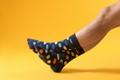Photo of Man in stylish colorful socks on yellow background, closeup