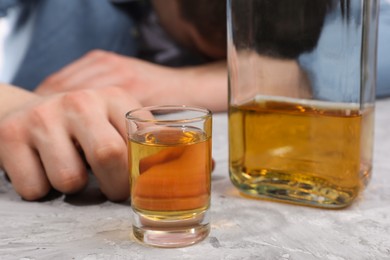 Alcohol addiction. Man with whiskey at grey textured table, selective focus