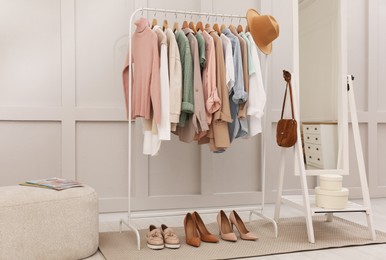 Rack with stylish women's clothes and mirror in dressing room