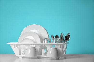 Photo of Set of clean dishware on table against color background