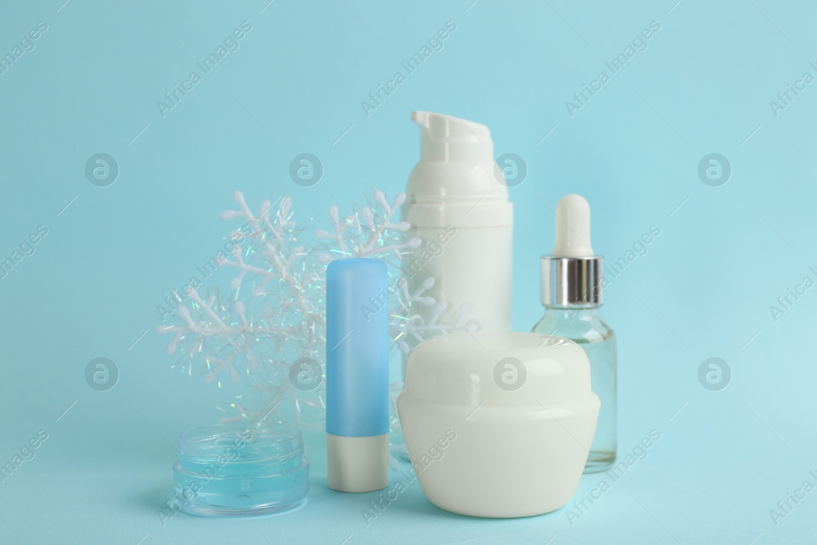 Photo of Beautiful composition with cosmetic products on cyan background. Winter care