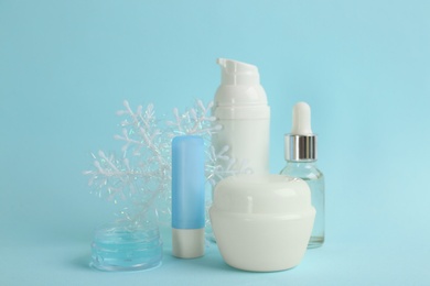 Photo of Beautiful composition with cosmetic products on cyan background. Winter care