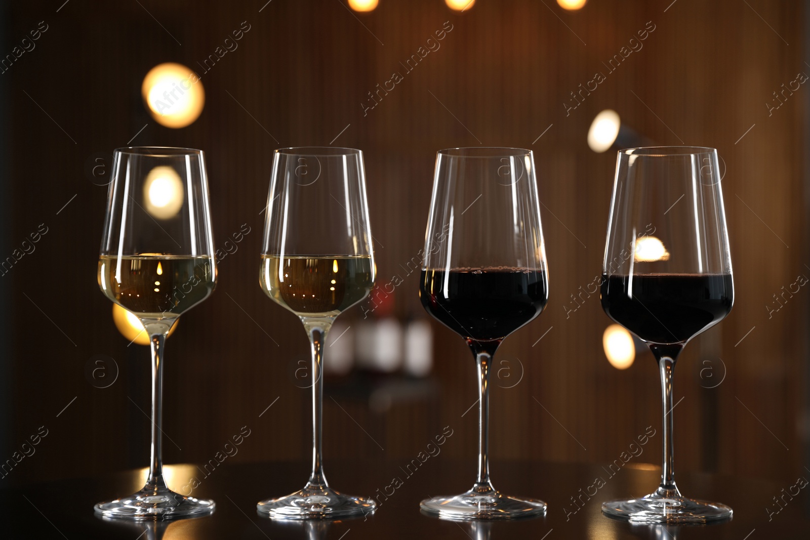 Photo of Glasses of different wines on table against blurred background