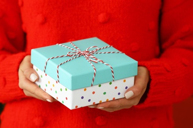 Photo of Woman in red sweater holding Christmas gift, closeup