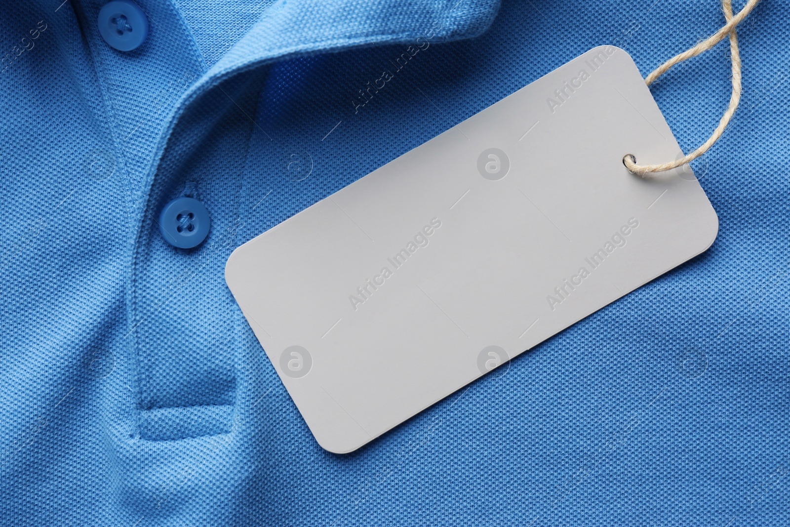 Photo of Cardboard tag with space for text on blue shirt , top view