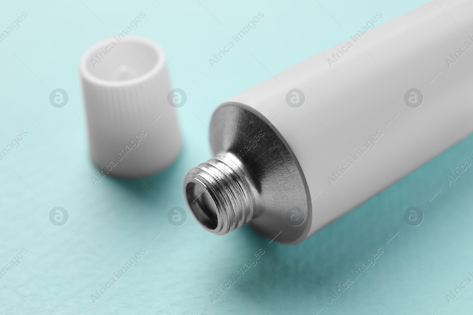 Photo of Tube of ointment on light blue background, closeup. Space for text