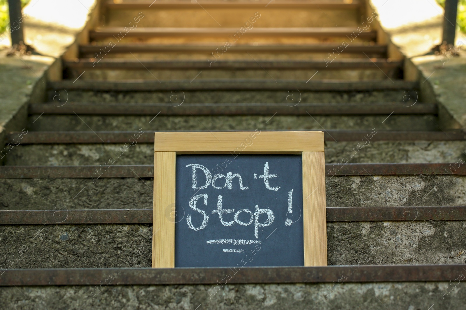 Photo of Chalkboard with phrase Don't Stop on stone stairs outdoors